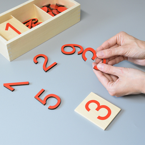 Kind ordnet rote Chips den Ziffern Montessori-Material gerade und ungerade Zahlen im Zahlenraum